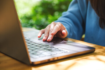 Closeup image of a woman working and touching on laptop computer touchpad