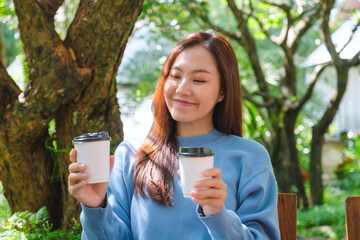 Poster - Portrait image of a young woman holding and serving two cups of coffee in the outdoors cafe