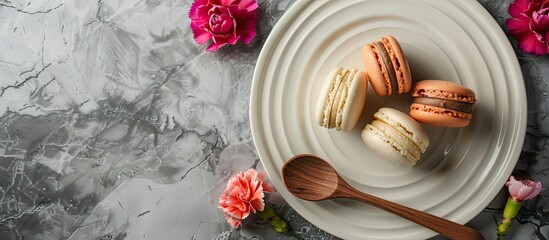 Poster - Macaroons on a white plate with a wooden spoon and carnation flowers top view still life copyspace