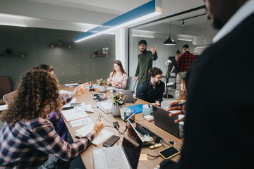 Wall Mural - A multicultural team of young professionals engaged in an animated business discussion in a modern office setting, analyzing graphs and statistics.