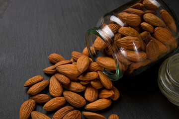 Poster - Almonds on black background. Glass jar full of almonds