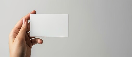 Leinwandbilder - A girl s hand is holding a blank business card The card is horizontal. with copy space image. Place for adding text or design