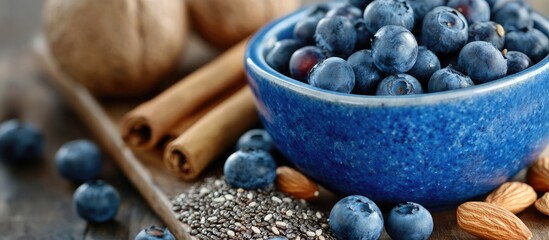 Leinwandbilder - Healthy natural food concept A close up of fresh blueberries in a blue bowl with blurry granola and chia seeds featured in a shallow depth of field On a wooden board there are some almonds cinnamon