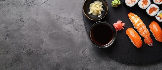 Leinwandbilder - Top view of various sushi pieces on a black slate plate accompanied by a bowl of sauce. with copy space image. Place for adding text or design