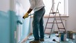 © PixelPerfectionist77 - Painter Applying Light Blue Paint to Room Wall