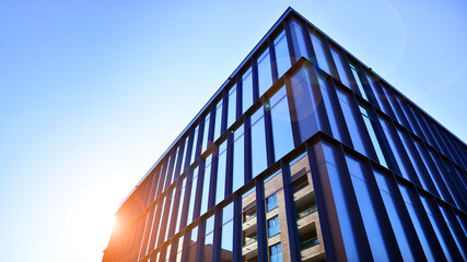 Exterior of modern building with many windows against blue sky, low angle view.