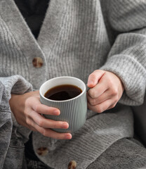 Wall Mural - Woman in grey cozy sweater holding mug with espresso coffee.