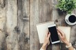 © Ahmed - Businesswoman hand holding a phone in office table with notepad and coffee cup