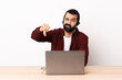 © luismolinero - Telemarketer caucasian man working with a headset and with laptop showing thumb down with negative expression.