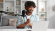 © YURII MASLAK - Microphone, podcast and Indian man speaker in his living room. Creative streamer, internet influencer or online content creator live streaming for audience.