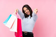 © luismolinero - Young woman with shopping bag over isolated pink background presenting and inviting to come with hand