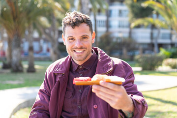 Wall Mural - Young caucasian man holding sashimi at outdoors with happy expression