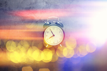 Background with a clock on the table and bokeh in pastel rainbow colors. Time for rest and travel.