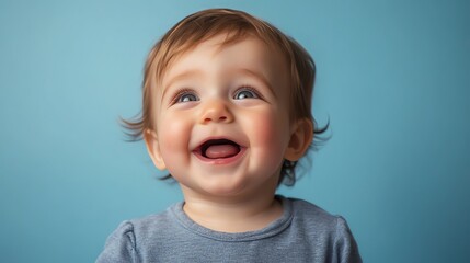 A baby with brown hair and blue eyes laughs.