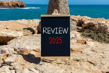 Planning review 2025 new year symbol. Concept words Review 2025 on beautiful yellow chalk blackboard. Beautiful stone beach blue sky sea background. Business review 2025 new year concept. Copy space.