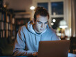 © Leonardo - Un joven estudiante universitario concentrado frente a su computadora portátil por la noche