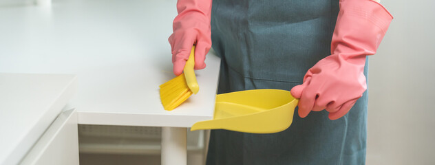 Wall Mural - Household hygiene clean up, housekeeper woman hand in pink rubber protective gloves with yellow broom and dustpan sweeping remove dust on table at home, equipment or tool for cleaning, cleaner people.