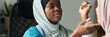 © pressmaster - Muslim medical professional wearing a hijab attending a patient in clinic environment, holding a medical device with focused expression, showing dedication and care for patient wellbeing