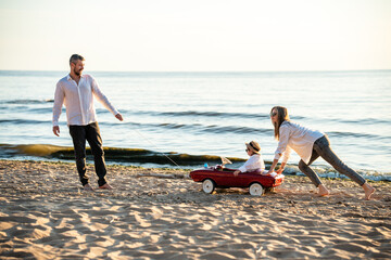 Happy young family having fun on sea shore. Mother, father and daughter on vacation.