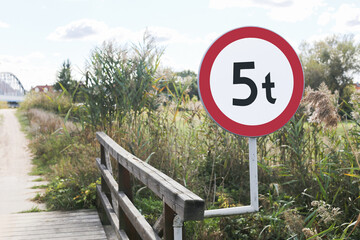 small wooden bridge with weight limit sign indicating maximum vehicle load of 5 tons. rustic structu