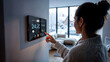 © guteksk7 - A woman lowers the temperature on a smart control panel, focusing on ecology and savings in the face of a potential energy crisis. The snowy landscape outside emphasizes the winter atmosphere.