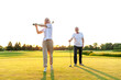 © Богдан Маліцький - old senior couple in white clothes playing golf on golf course and chatting at sunset, elderly man and woman actively relaxing outdoors and laughing, pensioners on vacation