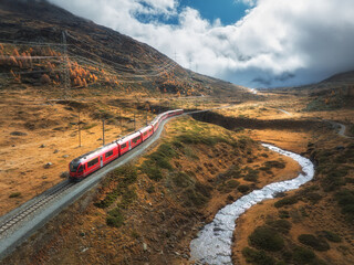 Wall Mural - aerial view of red train, river, mountains, orange hills in fall
