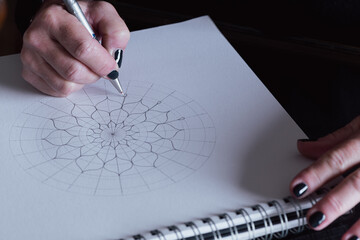 Woman drawing a pencil Mandala on paper