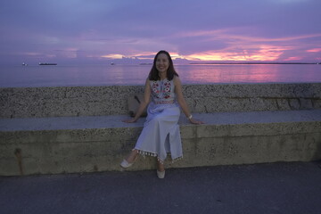 Asian woman tourist in adventure travel destination dress relaxing on the beach watching the sunset