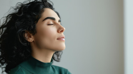 A confident brunette woman with curly hair gazes directly at the camera, wearing a vibrant green top against a white backdrop.