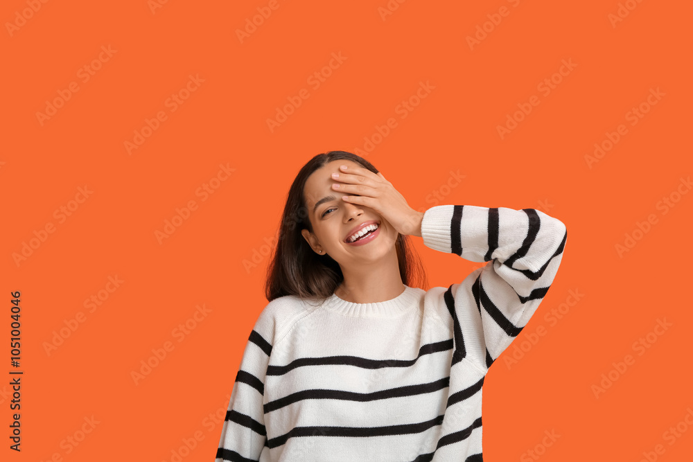 Beautiful young happy woman laughing on orange background