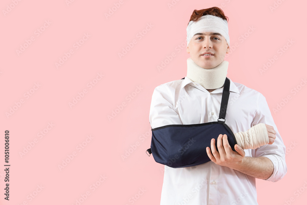 Injured young man after accident with broken arm on pink background
