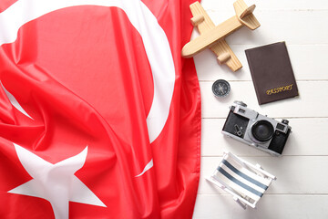 Flag of Turkey with mini beach chair, passport, compass, airplane and photo camera on white wooden background