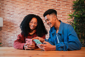 African American couple using their cellphones at home, smiling and sharing moments together, Two friends enjoying technology and connectivity in a cozy, modern living space with brick wall background