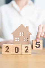 Happy New Year 2025 with house model. real estate, Home loan and mortgage, tax, investment, financial, savings and New Year Resolution concepts