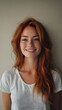 © Alona - A cheerful young woman with long red hair smiling against a neutral background.