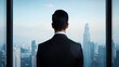 © JK_kyoto - Businessman gazing out at a city skyline from a high-rise office window.