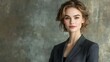 © 69 - A poised young Caucasian woman in gray office attire stands confidently against a stylish backdrop, ready for a promotional campaign with space for text.