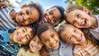 © Tekin - Low angle view of happy mixed race children embracing each other while smiling at camera. Cute little group of schoolchildren sticking heads together. Closeup face of girls and little boys embracing.