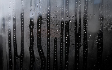 Poster - Close-up of raindrops running down a windowpane, creating a blurred background.