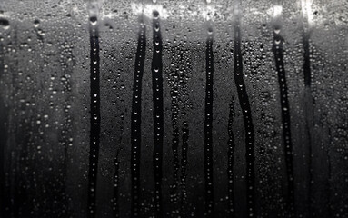 Poster - Close-up of water droplets on a windowpane, forming vertical streaks.