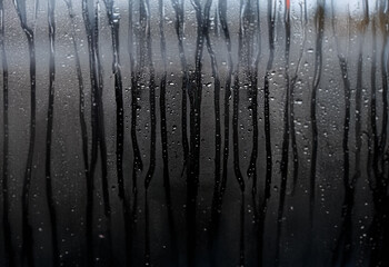 Poster - Raindrops on a windowpane, creating streaks and a blurry view of the outside world.