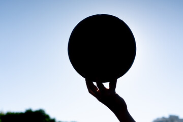 close-up a female hands with a basketball against the sky backlight ball in hand active leisure