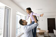 © fizkes - Joyful Indian father lifting girl up in air, holding kid with open hands in arms. Happy strong dad and little daughter child playing airplane at home together, enjoying active games in apartment