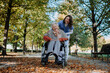 © Halfpoint - Disabled elderly woman in wheelchair on walk in the park during warm autumn day. Young nurse pushing wheelchair, talking with senior woman.