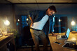 © peopleimages.com - Man, laptop and back injury at night in office with fatigue, stress and joint pain at startup. Person, computer and inflammation with burnout, tired and spine ache with deadline at creative agency