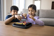 © fizkes - Positive cute Indian elder brother and younger sister kids playing board game with colorful balls in box, solving puzzle, enjoying family home activity, leisure, playtime, childhood together