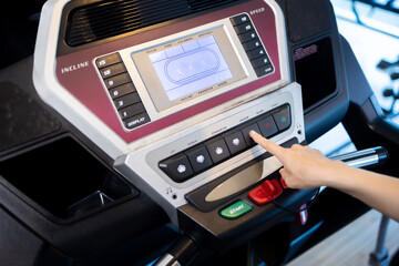 Woman is pressing the power button on a treadmill at a gym