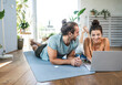 © Westend61 - Smiling man with woman using laptop and lying on mats at home