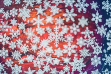 Poster - Close up single snowflake on red purple background with others out of focus.